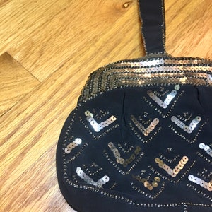 May include: A black evening bag with a gold and silver sequined design. The bag has a single strap and a rounded shape.