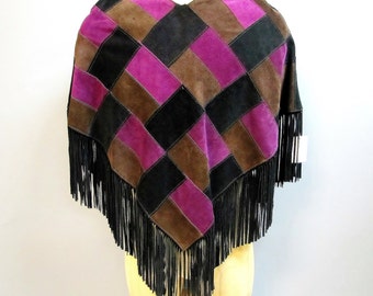 Può includere: Un poncho in pelle scamosciata marrone, nero e viola con frange nere.
