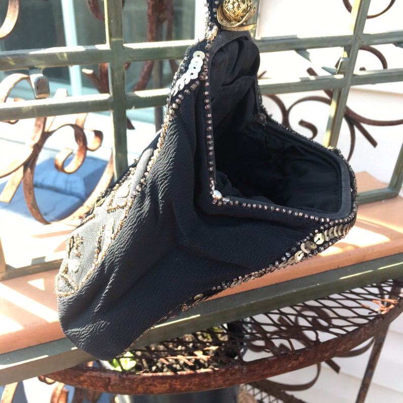 May include: A black beaded evening bag with gold sequins. The bag is closed and has a small metal clasp.
