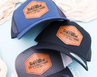 May include: Three trucker hats with a brown leather patch that says "Vista Street Farms Est. 2023". The hats are navy blue, black, and gray.