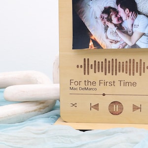 May include: A wooden photo frame with a clip to hold a photo. The frame has a laser-engraved design of a music player with a barcode and the text "For the First Time" by Mac DeMarco.