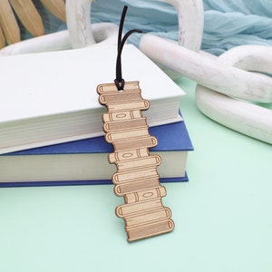 May include: A wooden bookmark shaped like a stack of books. The bookmark is brown and has a black string attached to the top.