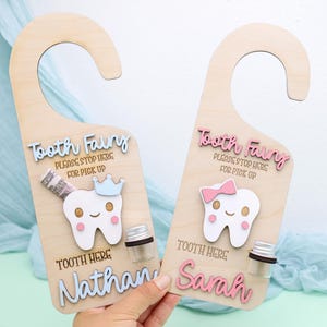 May include: Two wooden door hangers for the Tooth Fairy. Each has a tooth graphic, the words "Tooth Fairy" and "Please Stop Here For Pick Up". One says "Nathan" and the other says "Sarah".