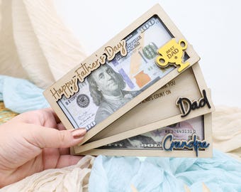 May include: Wooden Father's Day gift box with a $100 bill visible. The box has the words "Happy Father's Day" and "Best Dad" on it. Additional boxes say "Dad" and "Grandpa".