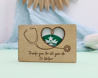 Puede incluir: Tarjeta de madera con un estetoscopio y un diseño de corazón. La tarjeta dice "Gracias por todo lo que haces Dr. Walker".