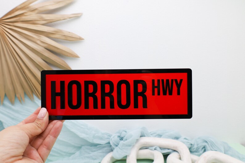 May include: A black and red rectangular sign with the text "HORROR HWY" in white.