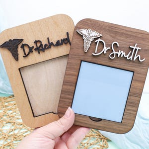 May include: Two wooden picture frames with a blank white space in the center. The frame on the left says "Dr. Richard" and the frame on the right says "Dr. Smith".