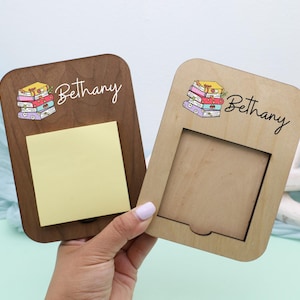 May include: Two wooden memo holders, one dark brown and one light brown, each with a stack of books illustration and the name "Bethany". The dark brown holder has a yellow sticky note attached.