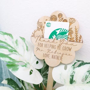 May include: Wooden flower-shaped sign with a gift card slot. The sign says "Thank you for helping me grow Mr. Robinson Love, Natalie".