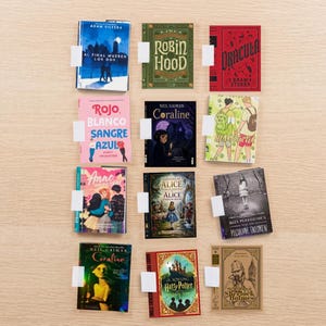 Puede incluir: Una colección de once libros en miniatura dispuestos en una cuadrícula, con varios títulos que incluyen Al Final Mueren Los Dos, Robin Hood, Dracula, Rojo Blanco Sangre Azul, Coraline, Heartstopper, Anne, Alice, Miss Peregrine y Sherlock Holmes.