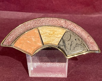 Könnte beinhalten: Eine goldfarbene Brosche mit Fächerform. Die Brosche besteht aus verschiedenen Steinsorten, darunter rosa, beige und grau.