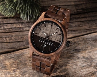 Puede incluir: Un reloj de pulsera de madera marrón con una esfera negra y una pantalla de día de la semana y fecha. El reloj tiene una correa de madera marrón con rayas negras.