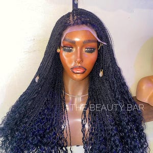 May include: A black braided wig with curly ends. The wig is styled in a long, flowing style and is worn on a mannequin head. The wig is made of synthetic hair and is designed to look like natural hair.