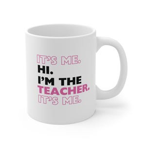 May include: White ceramic coffee mug with black text that reads "It's me. Hi. I'm the teacher. It's me." The word "teacher" is in pink.