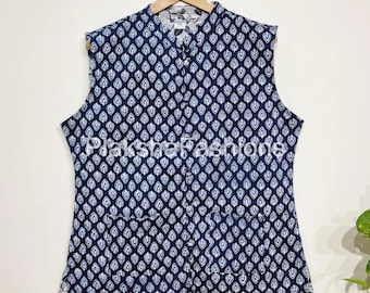 May include: A sleeveless navy blue vest with a repeating white teardrop pattern. The vest has a mandarin collar, a button-down front, and two front pockets. It is hanging on a wooden hanger.