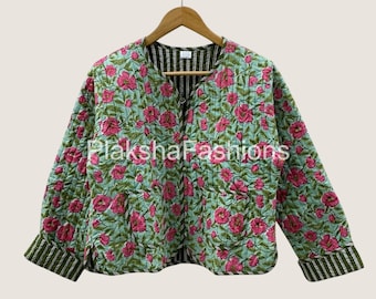 May include: A quilted jacket with a floral pattern. The jacket features a light blue background with pink flowers and green leaves. The cuffs and inner lining have a striped pattern. The jacket is hanging on a wooden hanger.