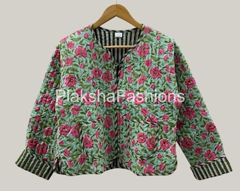 May include: A quilted jacket with a floral pattern of pink flowers on a light blue background. The jacket has a round collar and long sleeves with striped cuffs. The interior lining is striped. The jacket is hanging on a wooden hanger.