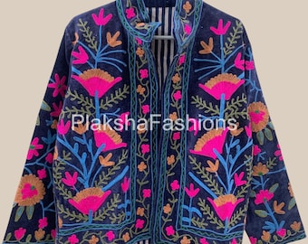 May include: A navy blue jacket with vibrant floral embroidery in pink, orange, and blue. The jacket features a high collar and a striped lining. The text "Plaksha Fashions" is visible on the front.
