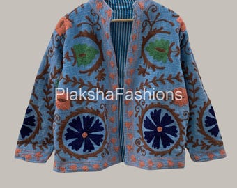 May include: A light blue jacket with floral embroidery in brown, orange, and green. The jacket has a mandarin collar and a striped lining. The text "PlakshaFashions" is visible on the front of the jacket.