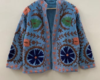 May include: A light blue embroidered jacket with floral patterns in brown, coral, and green. The jacket features a mandarin collar and a striped lining. The brand name "Plahisha Fashions" is printed at the bottom.
