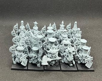 May include: A collection of miniature fantasy figures, likely for tabletop gaming. The figures are gray, detailed, and feature various ornate designs, including helmets, shields, and weapons. They are mounted on black bases, suggesting they are ready for play.