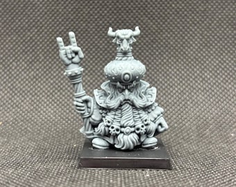 May include: A gray miniature figurine of a fantasy dwarf character. The dwarf has a large beard, a horned headpiece, and is holding a staff with a hand gesture. The figurine is on a black base.