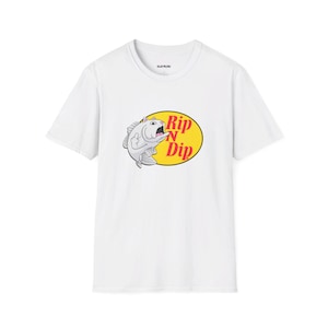 May include: White t-shirt with a cartoon fish graphic inside a yellow oval, featuring the text "Rip N Dip". The design is in red and white. The shirt has a crew neck and short sleeves. The graphic is centered on the front.