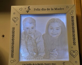 Könnte beinhalten: Ein weißer Holzrahmen mit einem Foto von zwei Kindern darin. Der Rahmen hat ein Herz- und Sternmuster um den Rand. Der Text "Feliz día de la Madre" befindet sich oben am Rahmen. Der Text "Con Cariño, de tu Marido, Noemí y Marc" befindet sich unten am Rahmen. Das Datum "5 de Mayo del 2024" befindet sich ebenfalls unten am Rahmen.
