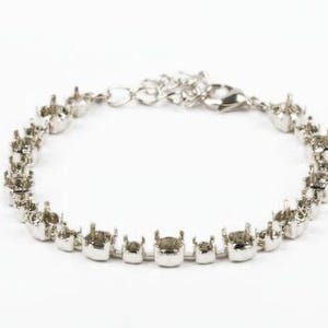 May include: Silver bracelet with a row of round settings for rhinestones. The bracelet has a lobster claw clasp.