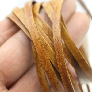 May include: Close-up of a bundle of brown leather cord. The cord is smooth and has a slightly textured surface.