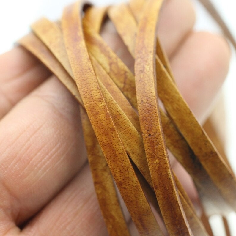 May include: Close-up of a bundle of brown leather cord. The cord is smooth and has a slightly textured surface.