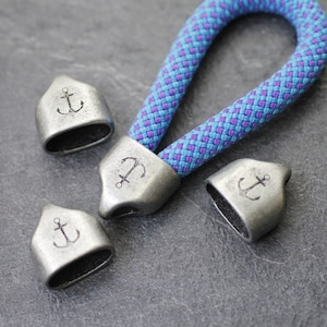 May include: Four silver-toned metal anchor-shaped zipper pulls with a blue and purple braided cord.