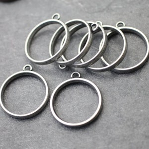 Peut inclure: Six attaches de pendentif en métal argenté de forme ronde avec une boucle en haut.