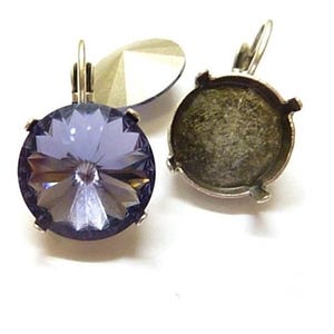 May include: Close-up of two lever-back earrings. One earring features a large, faceted, round, lavender-colored crystal. The other earring shows the back with a metal setting. The earrings are set against a white background.