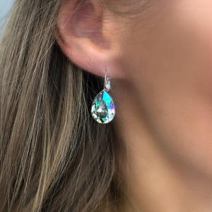 Puede incluir: Un par de pendientes de plata en forma de lágrima con piedras de cristal iridiscentes.