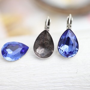 Puede incluir: Tres pendientes en forma de lágrima con engastes plateados. Los pendientes se muestran con y sin las piedras de cristal azules.