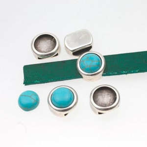 May include: Silver-toned metal bead caps with turquoise stones. Some caps are round, some are oval, and one is rectangular. The caps have a hole for threading.