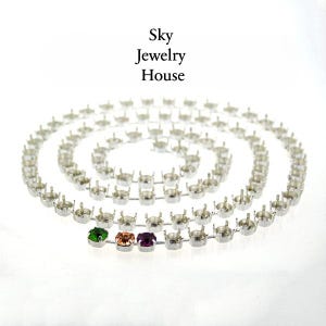 Puede incluir: Una cadena de plata con pequeños engastes redondos para piedras de cristal. Se muestran tres piedras de cristal en los engastes: verde, melocotón y morado.