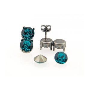 May include: A pair of silver stud earrings with two teal blue round gemstones. The earrings are shown with extra gemstones and earring backs.