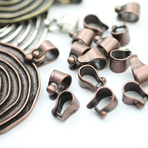 Op de afbeelding: Een close-up van een groep koperkleurige metalen springringen. De ringen zijn allemaal even groot en even gevormd, en ze zijn in een willekeurig patroon gerangschikt. De ringen worden gebruikt voor het maken van sieraden en andere ambachten.