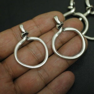 May include: Two silver-toned metal rings with a knotted design. The rings are open and have a smooth, polished finish.