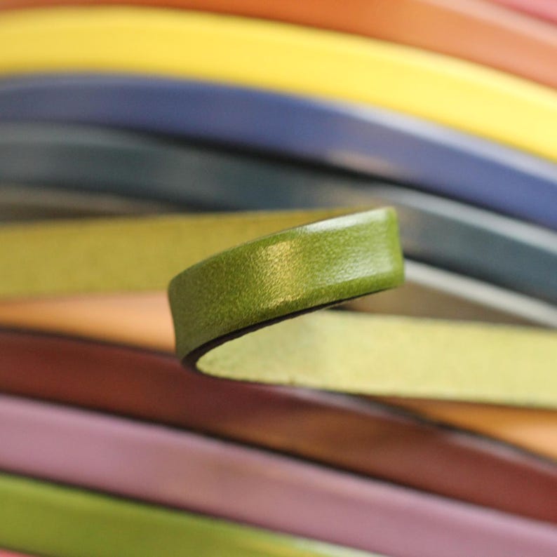 May include: A close-up of a green leather strip, with a dark edge, against a background of colorful leather strips.