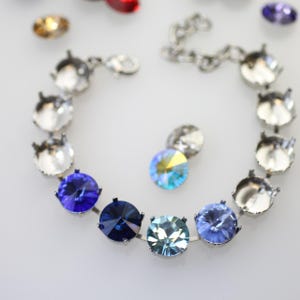 May include: A silver bracelet with a chain and a row of clear, blue, and light blue crystal settings.