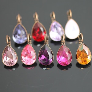 Puede incluir: Surtido de ocho colgantes de cristal en forma de lágrima con un aro de metal de color bronce antiguo. Los cristales son de varios colores, incluyendo rosa, morado, rojo, naranja y blanco.