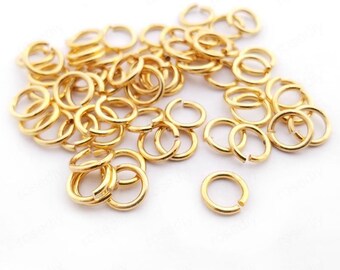 May include: A large pile of gold jump rings. The rings are small and have a smooth, shiny finish.
