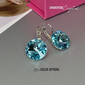 Puede incluir: Un par de pendientes de aro plateados con un cristal redondo azul claro en el centro. Los pendientes están hechos con cristales de Swarovski. 90+ opciones de color.