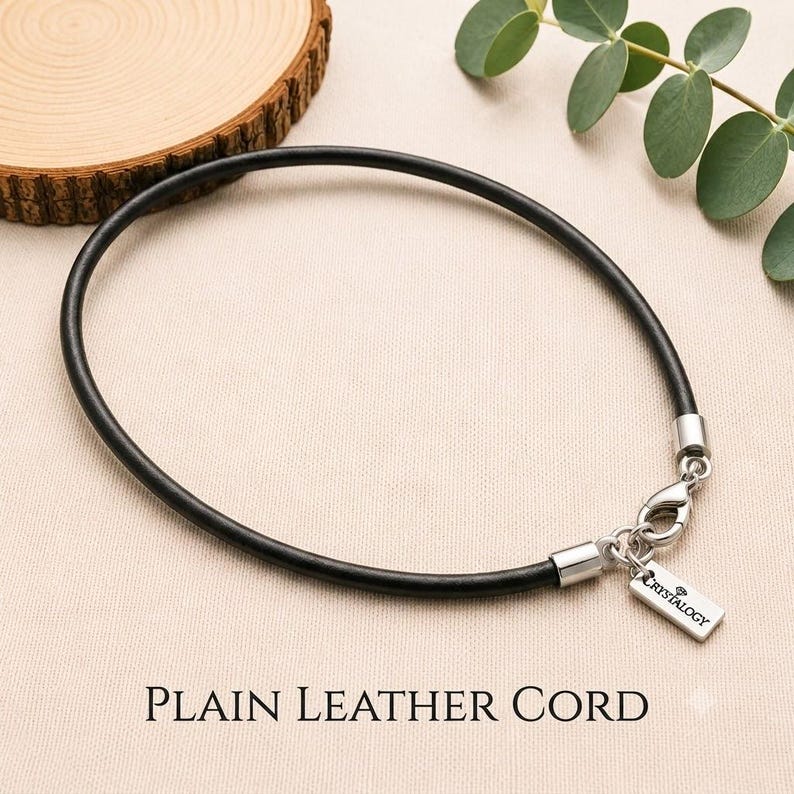 Pode incluir: Um colar de cord&atilde;o de couro preto com terminais de metal prateado e um fecho lagosta. Uma pequena etiqueta retangular de metal prateado est&aacute; presa ao fecho, gravada com o nome da marca Crystalogy e um pequeno &iacute;cone de diamante.
