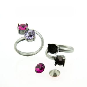 Może przedstawiać: Srebrne pierścionki o spiralnym wzorze, każdy z oprawą na dwa kamienie szlachetne. Jeden pierścionek prezentuje różowy i fioletowy kamień szlachetny. Luźne różowe i szare kamienie szlachetne również sugerują materiały do tworzenia biżuterii.