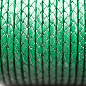 Puede incluir: Primer plano de un cordón de cuero trenzado verde. El cordón está hecho de múltiples hebras de cuero que se tejen juntas para crear un patrón de diamante.