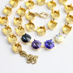 May include: Gold chain necklace with a clasp closure. The chain is adorned with round settings for rhinestones. Three rhinestones are set in the chain, one blue, one purple, and one iridescent.